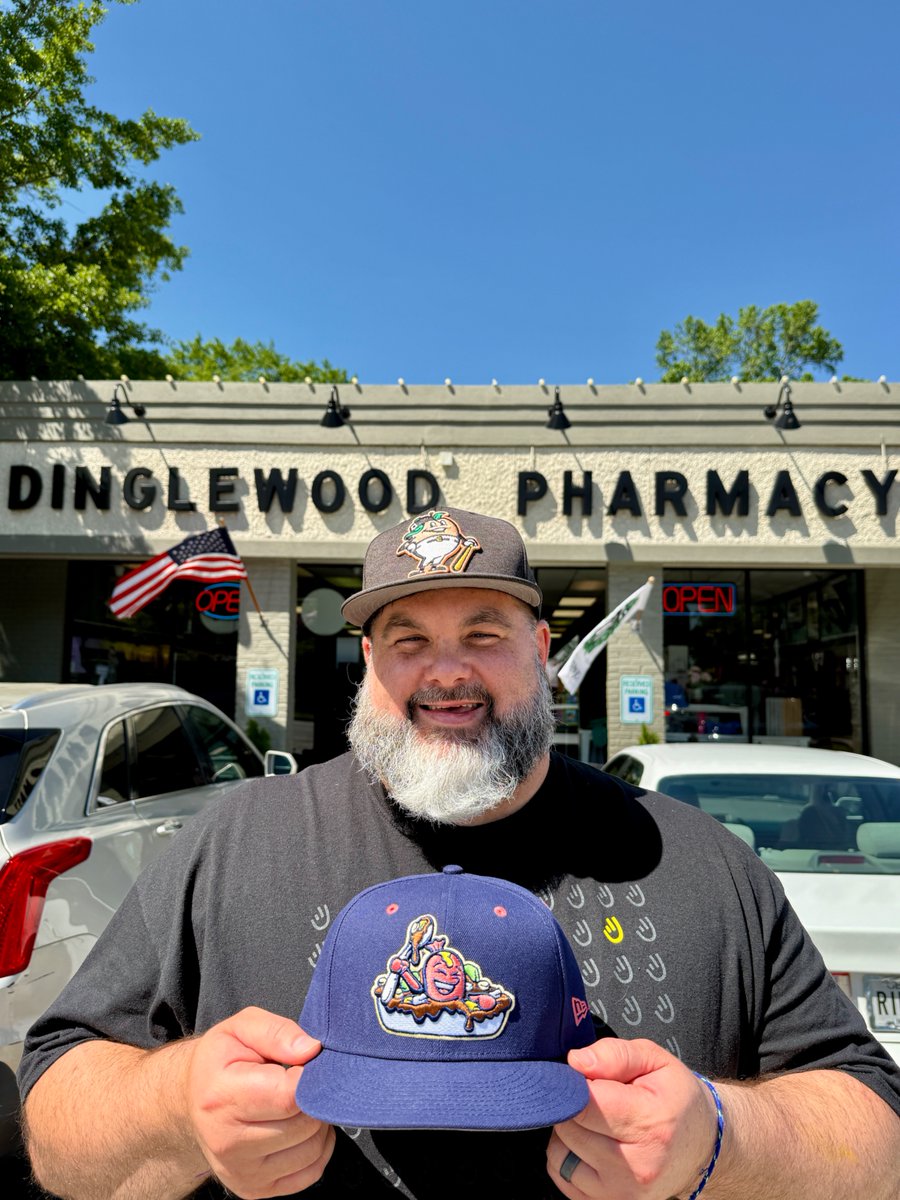 Mike Jones holding a Columbus Scrambled Dogs cap in front of Dinglewood Pharmacy in Columbus, Georgia